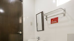 A small, clean bathroom with a toilet, sink, and mirror. A red sign above the mirror advises travelers to save resources. - Vaccinated Staff - OYO 850 Clr Mn Inn (Quezon City)
