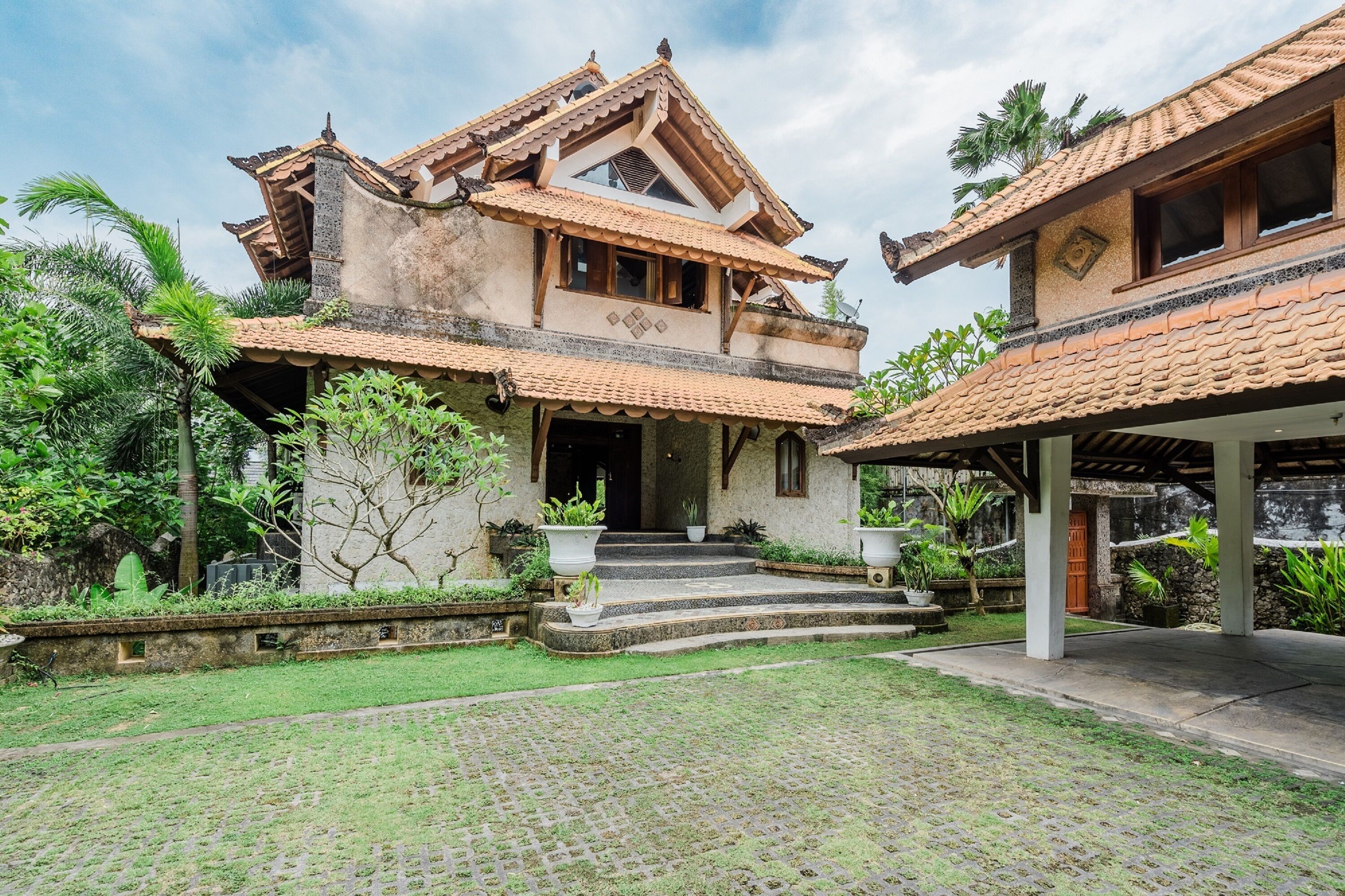 A traditional building with a tiled roof, a central staircase, and a covered porch area.