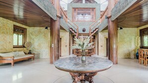 A spacious lobby with a central round table, wooden staircase, and a decorative vase with flowers. - AV Villa Canggu Hearts (Canggu)