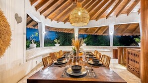 A dining area with a wooden table set for six, surrounded by wicker chairs. - AV Villa Canggu Hearts (Canggu)