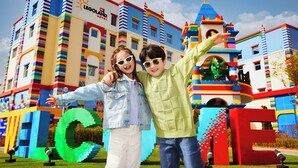 Un edificio colorido con fachada de estilo LEGO, un llamativo letrero que dice 'LEGOLAND HOTEL' y una gran estructura en forma de 'C' al frente.