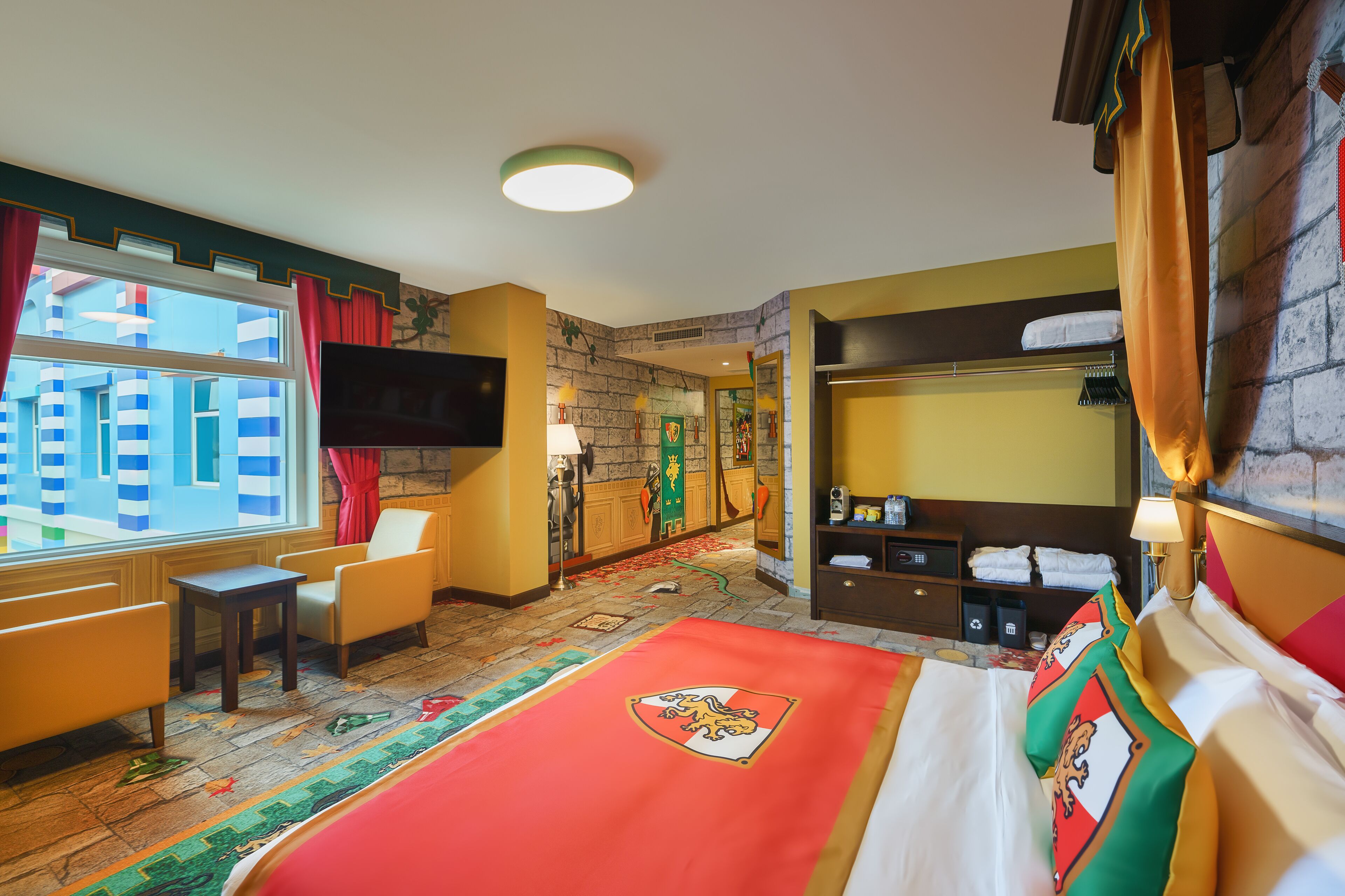 Una habitación de hotel con una cama grande, un escritorio, una silla, un televisor, un armario y una ventana con cortinas.