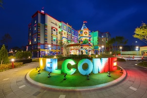 Un hotel muy iluminado con fachada colorida y un gran letrero luminoso de bienvenida.