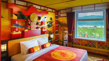A hotel room with a bed, a window with a view of a cityscape, and a decorative wall with a dragon design.