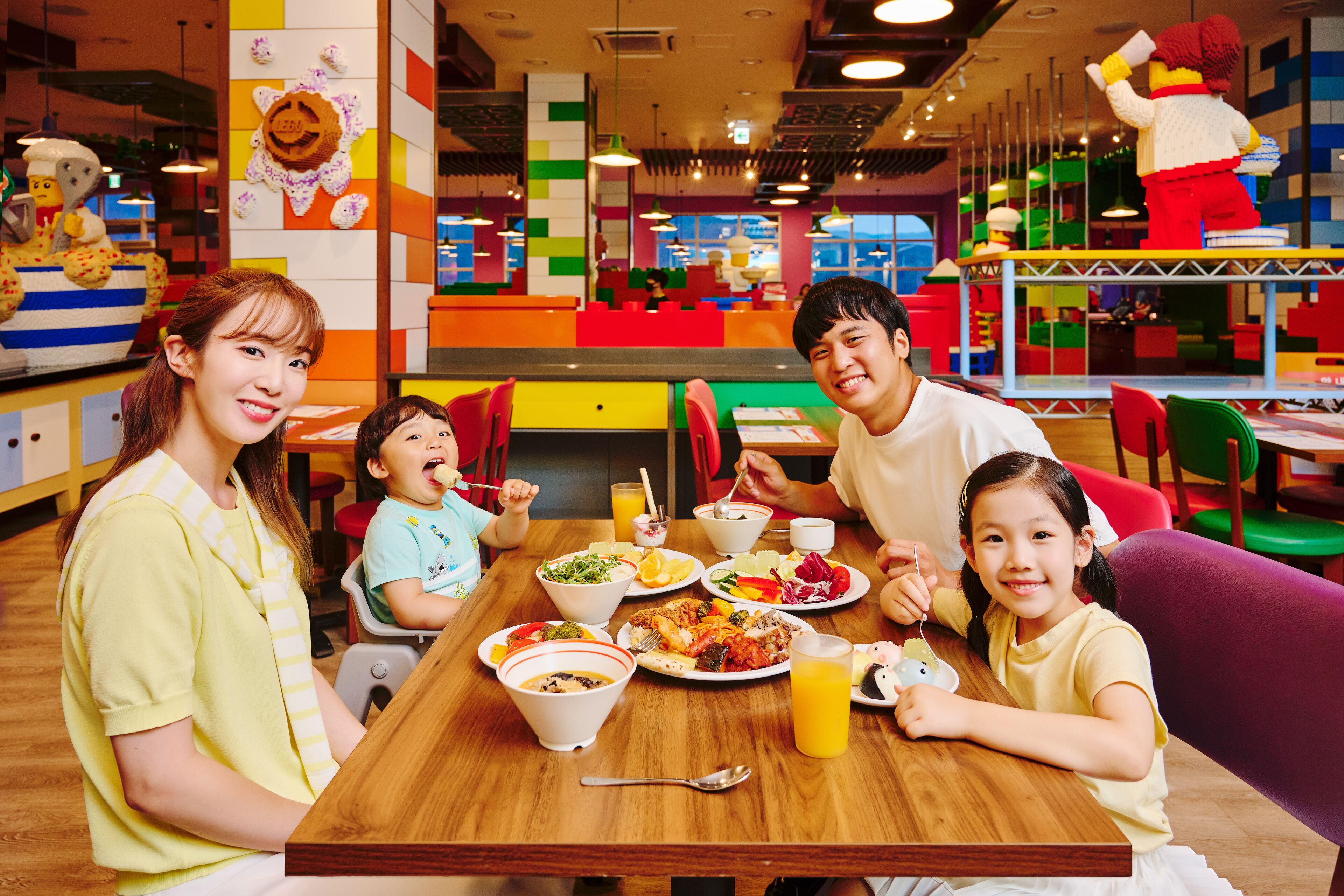 A family dining at a brightly colored restaurant with a variety of dishes on the table.