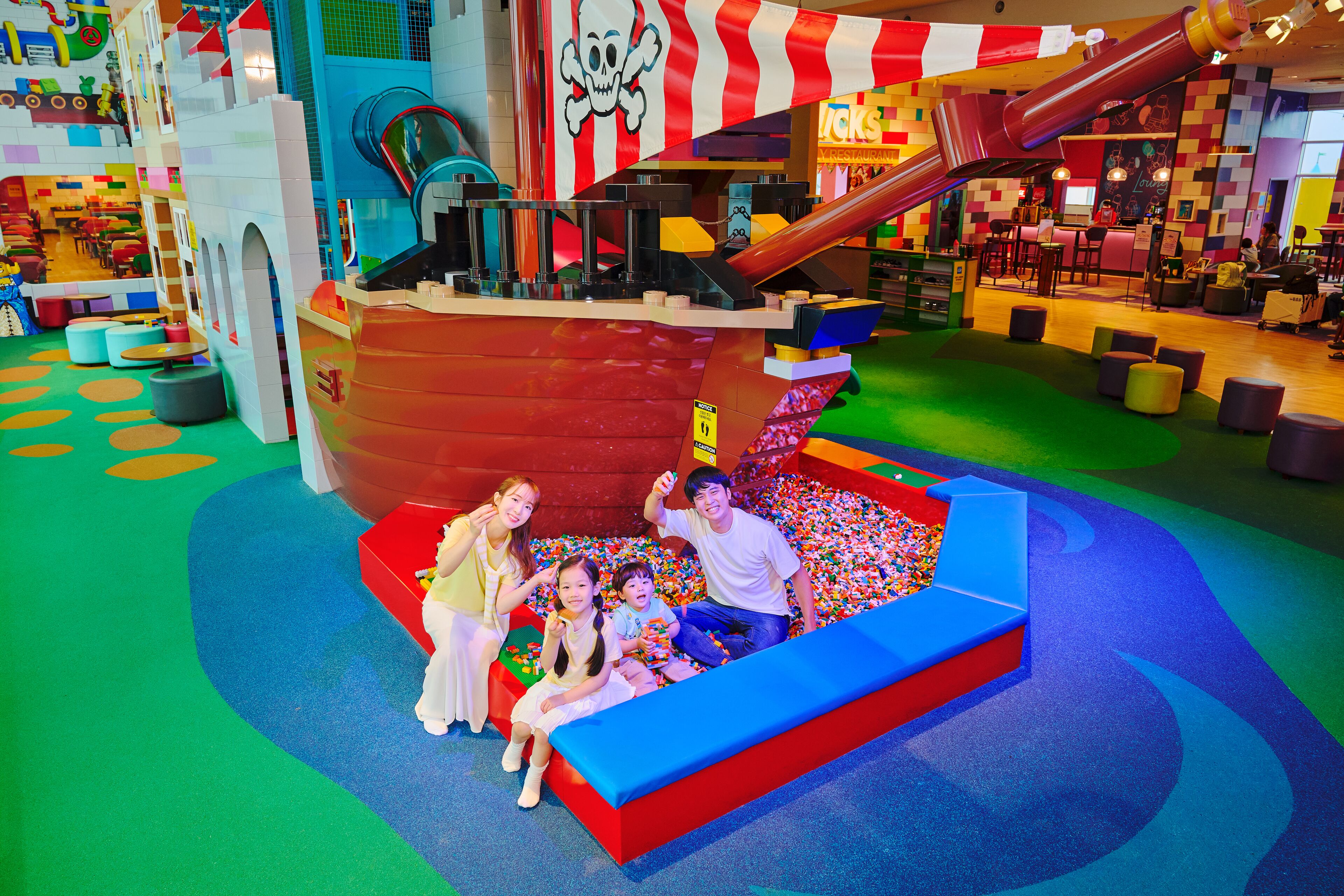 A play area with a pirate ship play structure, a slide, and colorful seating areas.