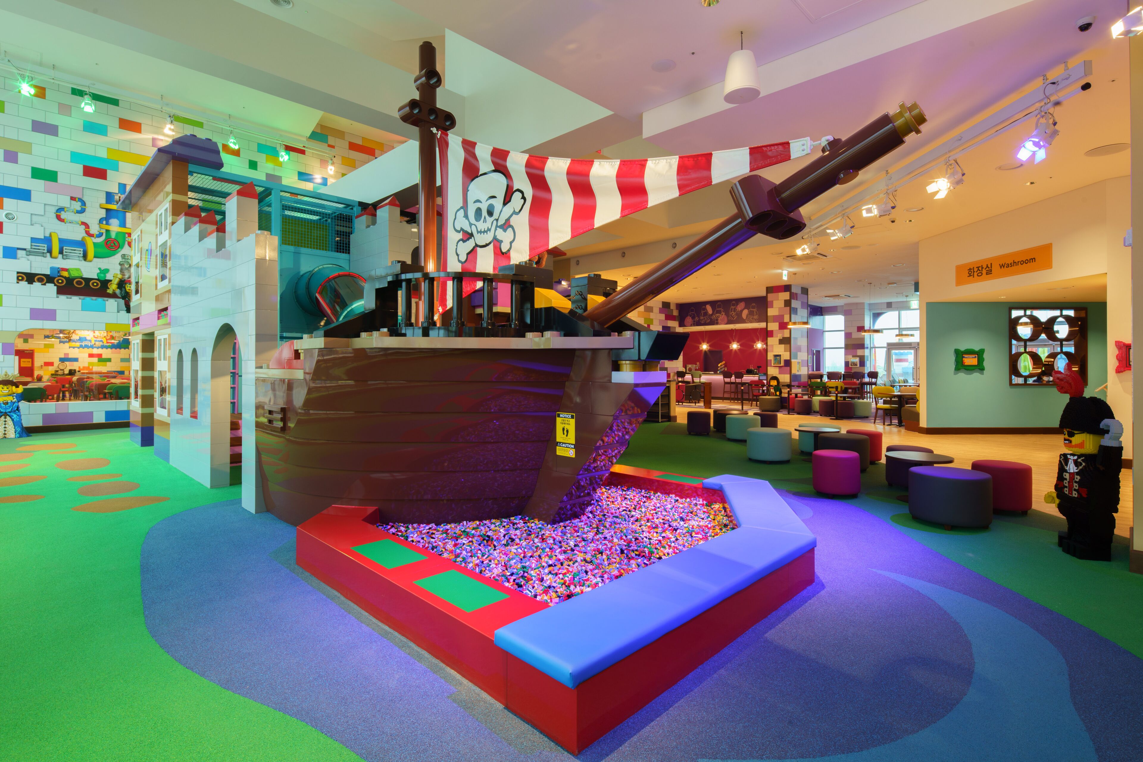 Un espace de jeux pour enfants avec une structure de jeu en forme de bateau de pirates, des murs aux couleurs vives et une piscine à balles.