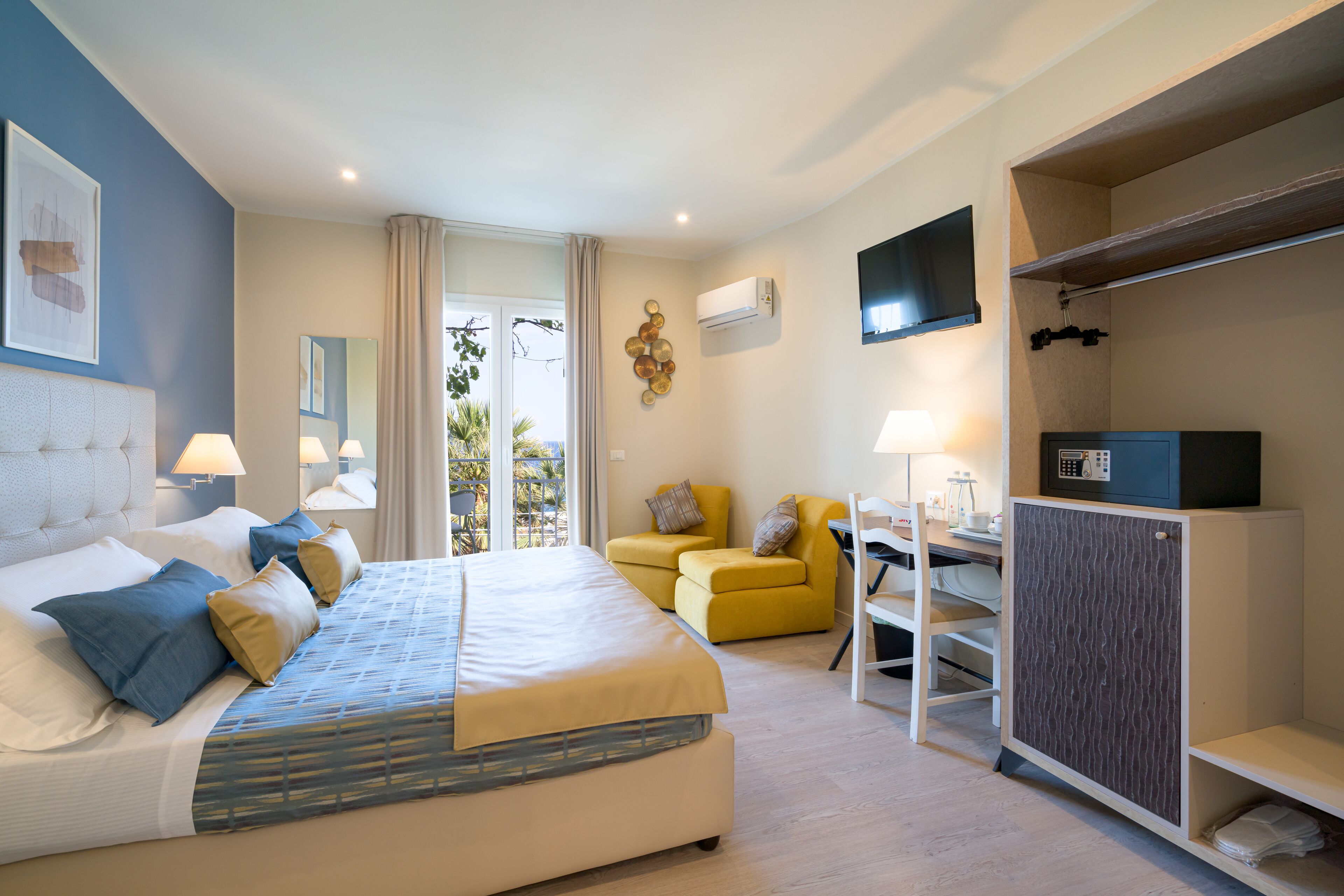 A hotel room with a bed, a desk, a chair, and a wardrobe.