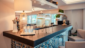 A bar area with a tiled backsplash, clear glass decanters, and a large lamp.