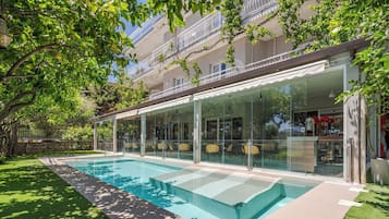Relax by the pool surrounded by lush greenery and a well-maintained lawn.