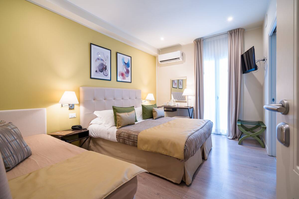 Una habitación de hotel con dos camas, un escritorio, una silla y un televisor.