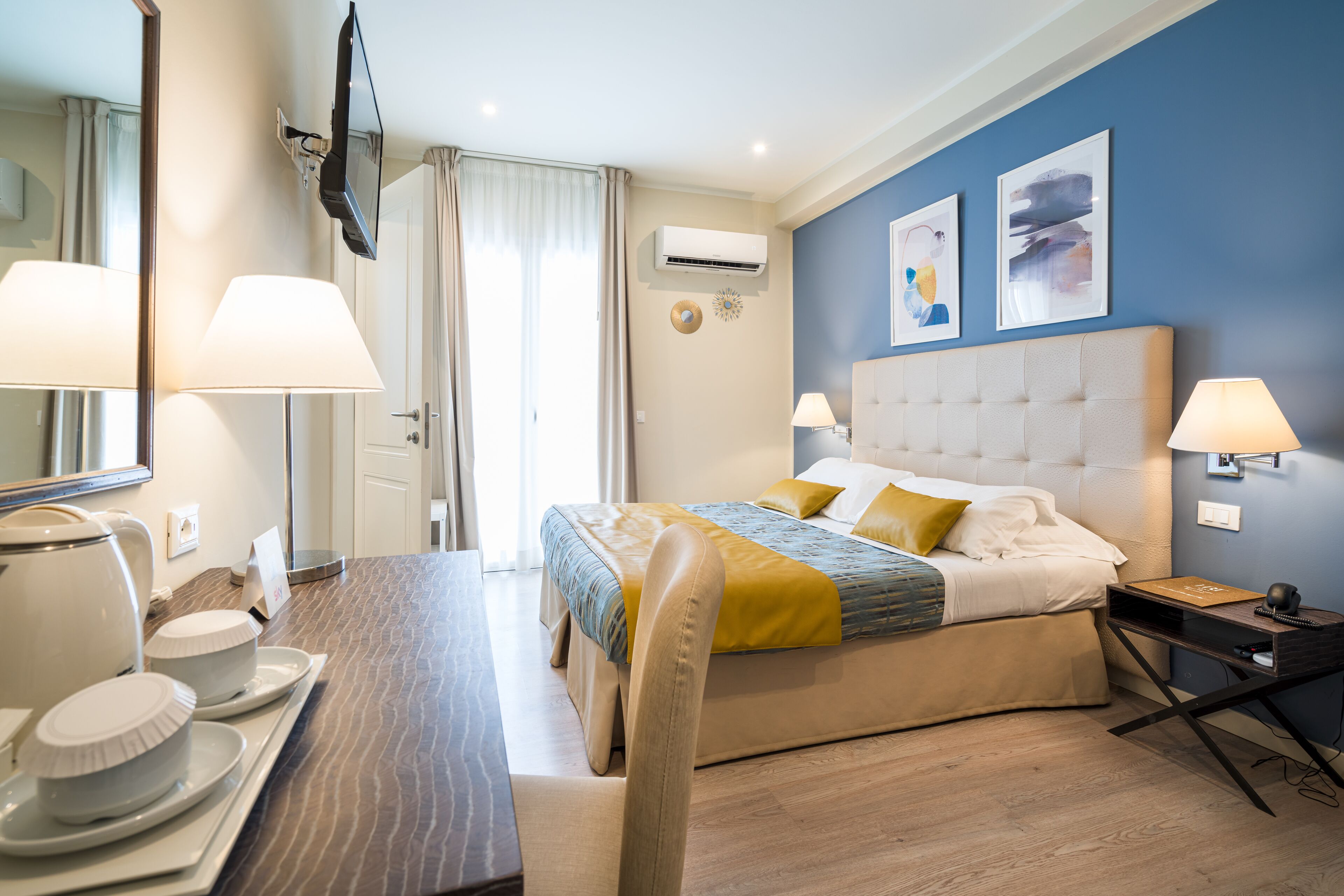 Une chambre d’hôtel moderne dotée d’un grand lit, de lampes de chevet, d’un téléviseur à écran plat et d’un coin repas avec une table et des chaises.