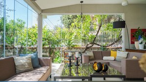 A modern living room with a glass coffee table, sofas, and a bookshelf.