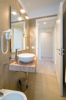Un baño moderno con un lavamanos grande, un espejo y un secador de pelo en la pared.