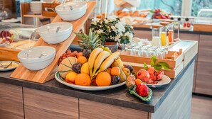 A breakfast buffet with various fruits, bowls, and beverages.