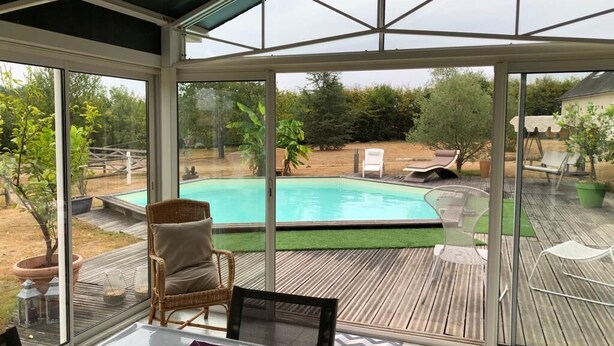 Un hivernacle amb vistes a una piscina, mobles d'exterior i un pont de fusta.