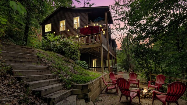 Une cabane dotée d’une terrasse, de meubles de jardin et d’un foyer extérieur.