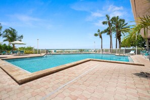 A rectangular swimming pool with a tiled deck, surrounded by lounge chairs and palm trees. - Beachfront! Gorgeous Views! Pool, Hot Tub, Tennis Courts, Fitness Room ~ 5F Crescent Beach Club (Clearwater)