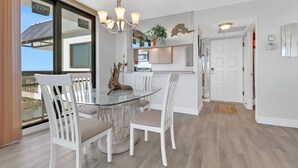 A modern kitchen with white cabinets, a glass dining table, and a chandelier.