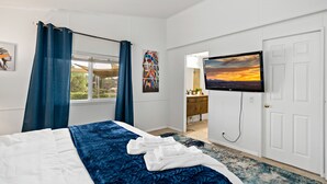Ett hotellrum med en säng, en TV, ett badrum och utsikt över omgivningarna.