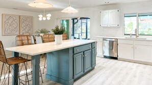 Una cocina moderna con una isla central, iluminación colgante y vistas al exterior.
