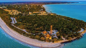 Vista aérea de una zona costera con un faro, playa y edificios residenciales.