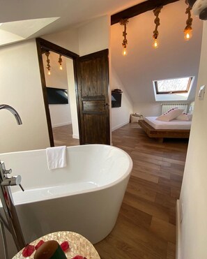 A modern bathroom with a freestanding bathtub, a wooden floor, and a skylight above the bed. - Baby Hotel (Turin)