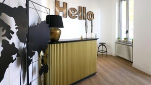 A modern kitchen with a black and gold color scheme, a 'Hello' sign on the wall, and a window with a view. - Baby Hotel (Turin)