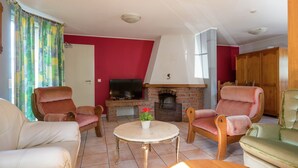 Ein Wohnzimmer mit Kamin, roten Wänden und einem Fernseher.
