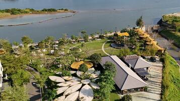 An aerial view of a residential area with a lake, mountains, and a parking lot with vehicles.