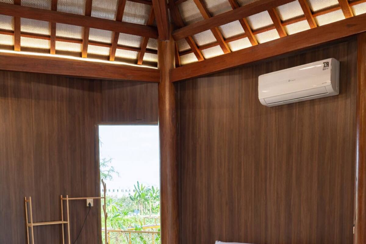A bedroom with a bed, a wooden ladder, a woven basket, and a small table.