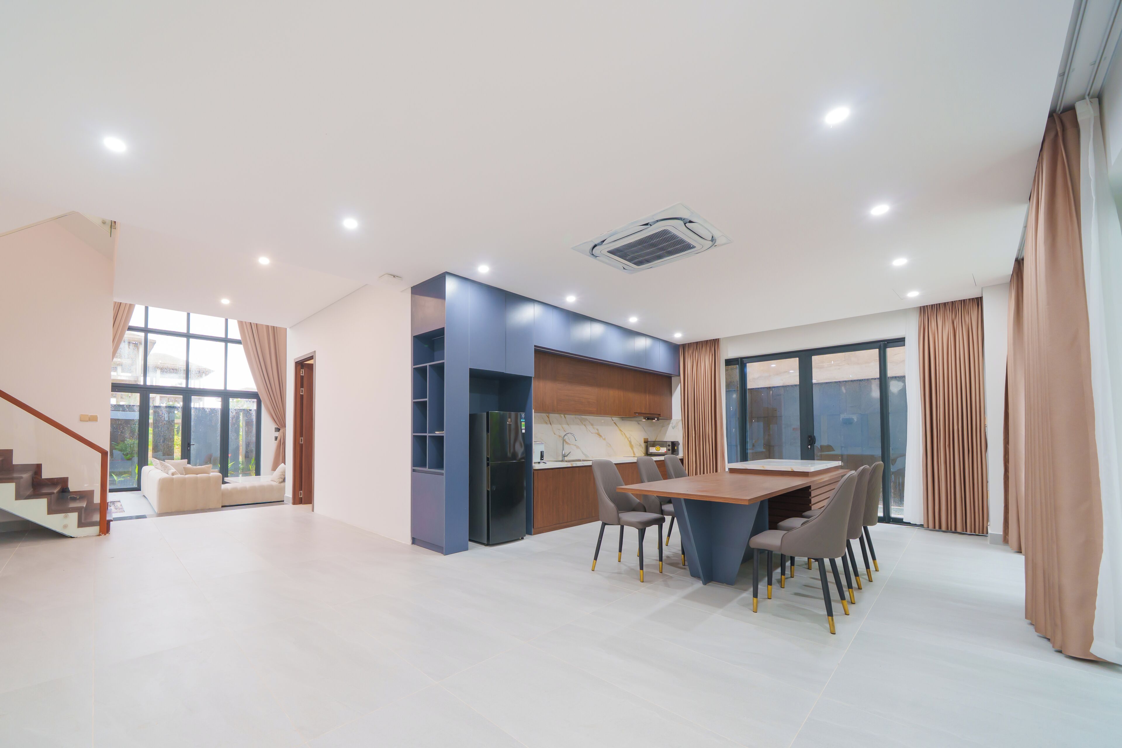 A modern kitchen with a dining area, built-in cabinets, and a large window.