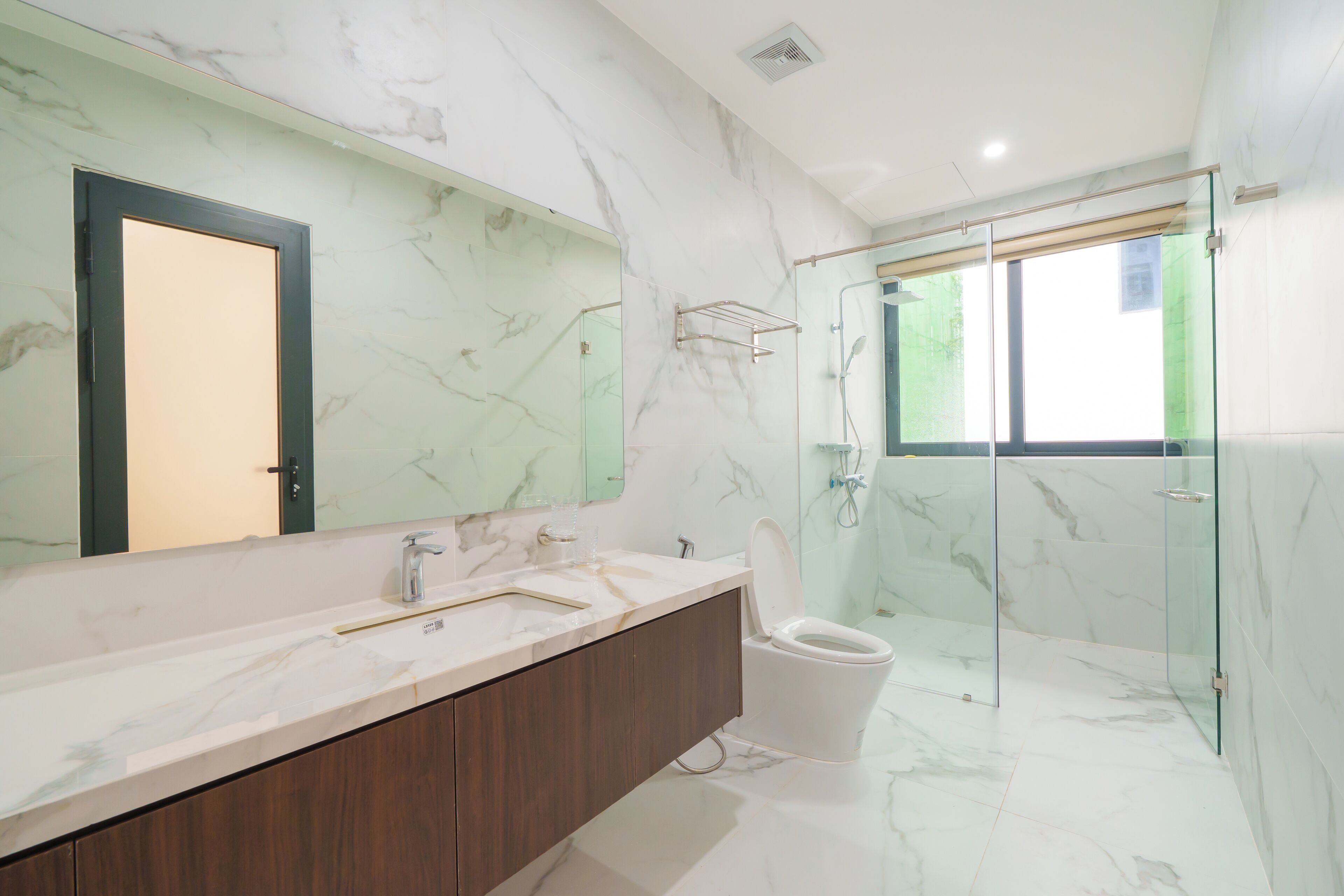 Un baño moderno con tocador de mármol, cabina de ducha de vidrio y un inodoro.