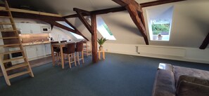 A loft-style room with a kitchen, dining area, and a large window.