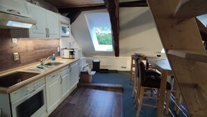 A compact kitchen with white cabinets, a Bosch dishwasher, and a window overlooking a garden. - Large loft apartment, private entrance, e-charging station and free parking space (Schwerin)