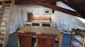 A loft-style kitchen with a wooden table, brown chairs, and a wooden ladder. - Large loft apartment, private entrance, e-charging station and free parking space (Schwerin)