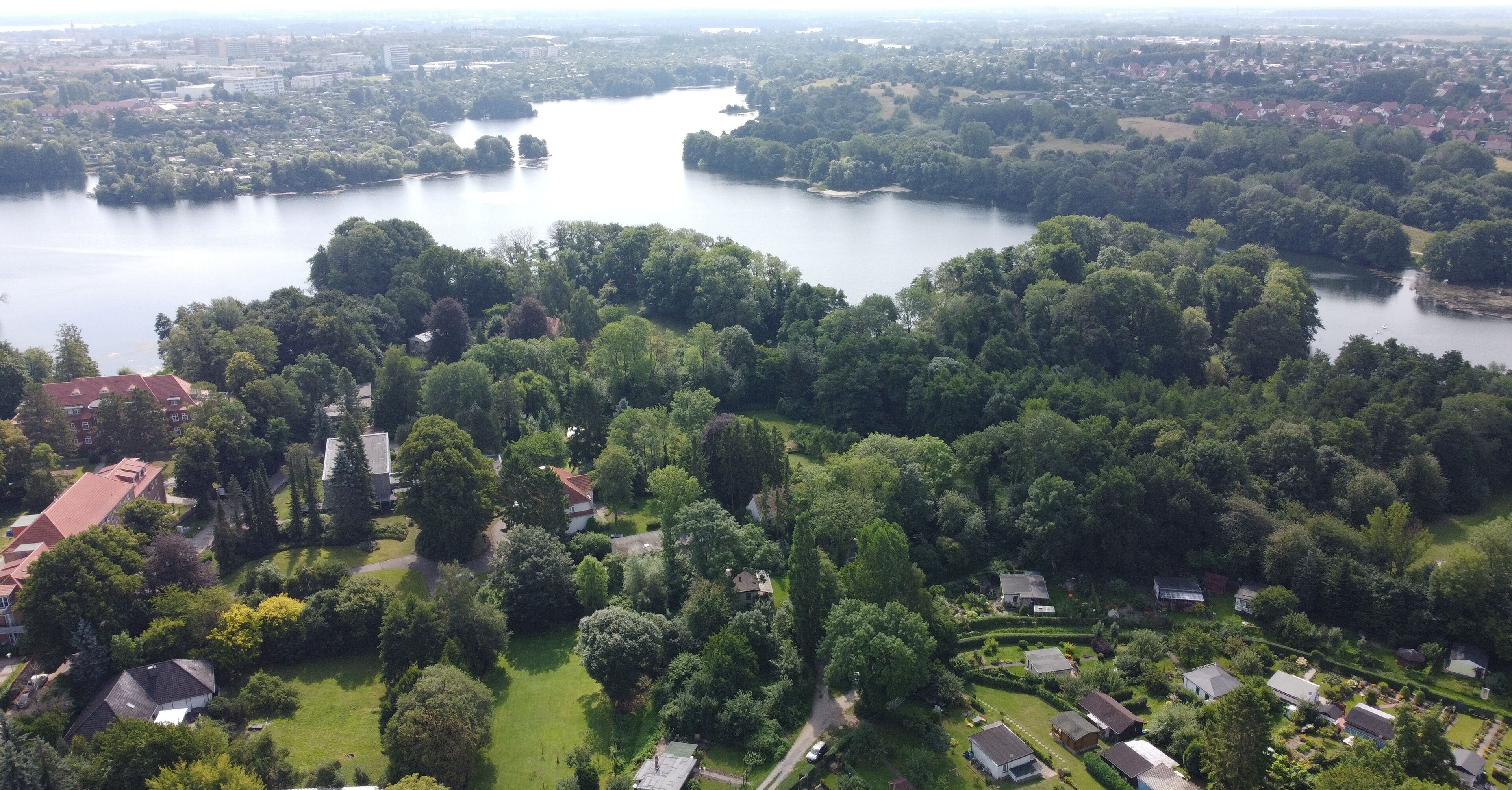 Luchtbeeld van een woongebied met huizen, groene ruimtes en een groot waterlichaam.