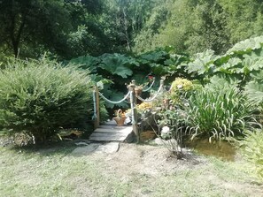 A garden pathway leading to a wooden structure surrounded by lush greenery and various plants. - 10 minutes from the beach and on the banks of a river, country house (Plouigneau)