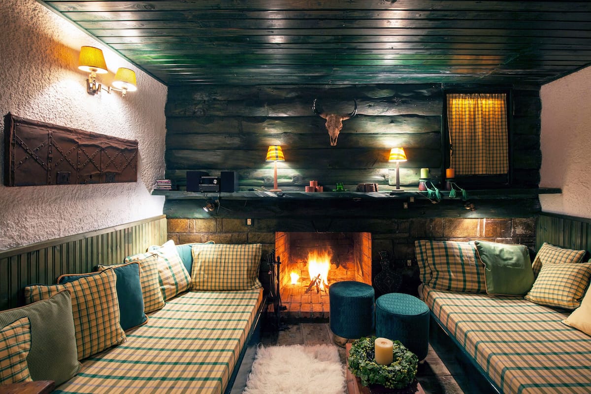 Ein gemütliches Zimmer mit einem karierten Sofa, einem Kamin und einer Holzbalkendecke.