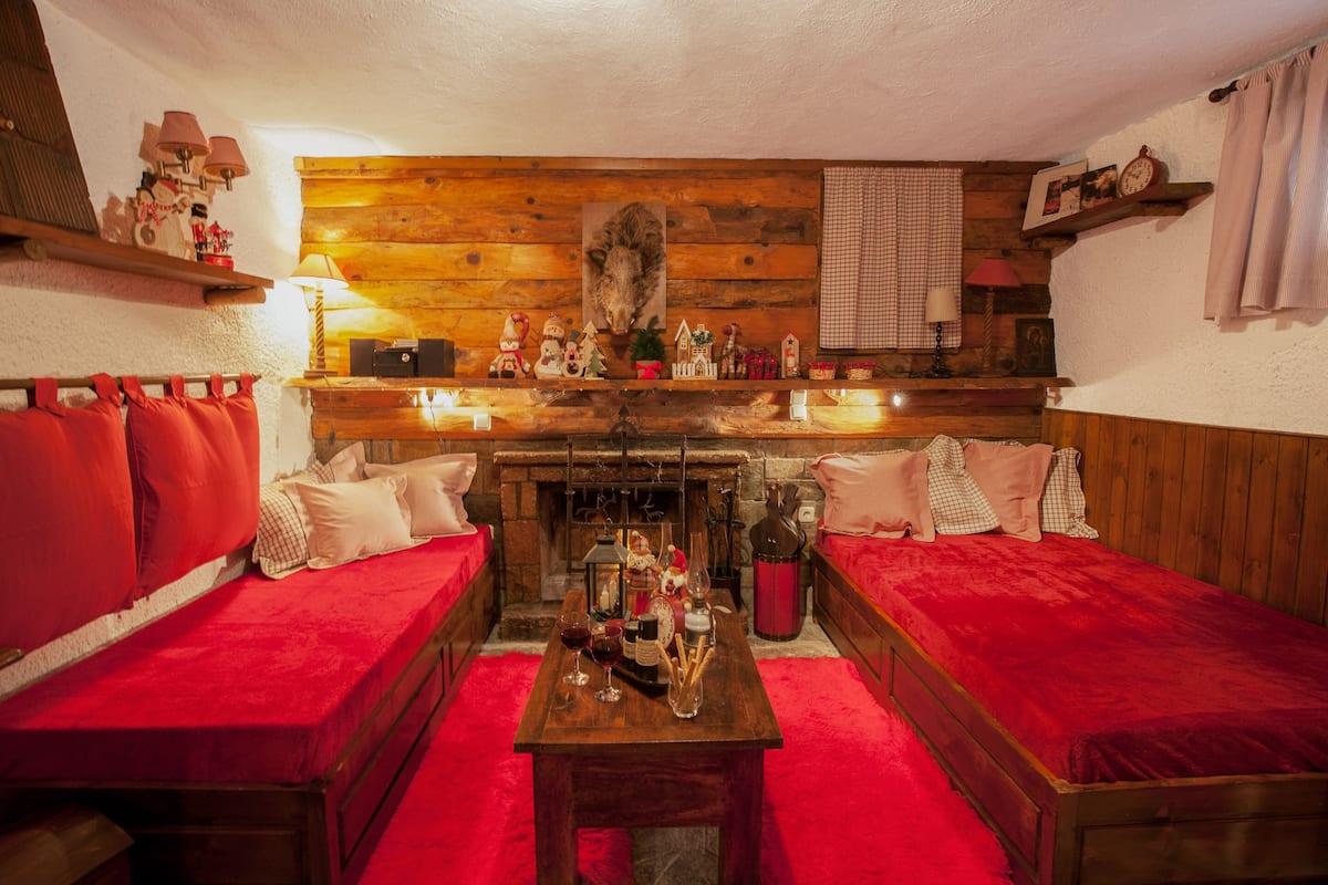 Ein gemütliches Zimmer mit zwei roten Polstersofas, einem Holztisch mit Getränken und einem Kamin.