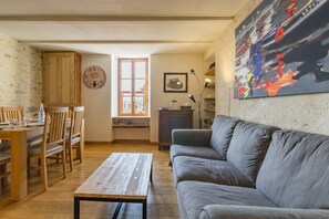 Una sala acogedora con un sofá, una mesa de madera y un comedor con sillas.