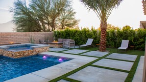 A swimming pool with a hot tub, a patio with chairs, and a well-maintained lawn. - A modern vacation home in Desert Hot Springs, built in 2020 with 4 bd, 3 baths (Desert Hot Springs)