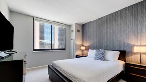 Un dormitorio moderno con una cama grande, un escritorio y una ventana.