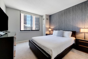 A modern bedroom with a large bed, a desk, and a window. - Stylish White Plains 2 Bed, By Metro-North Transit (White Plains)