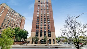 Un edificio alto de varios pisos con un diseño arquitectónico moderno, que presenta una serie de ventanas y una entrada central.