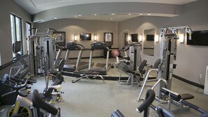 Un gimnasio con cintas de correr, elípticas y equipo de pesas.