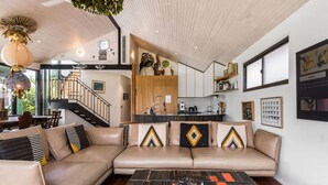 Un salon moderne avec un canapé beige, une table basse et un escalier menant à un niveau supérieur.