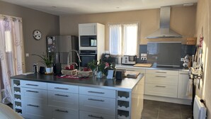 A modern kitchen with white cabinets, a central island, and a large window. - Villa with heated pool and jacuzzi Sarlat en Périgord Noir (Saint Vincent le Plauel)
