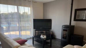 A living room with a sofa, a TV, a small table with candles, and a fireplace. - Villa with heated pool and jacuzzi Sarlat en Périgord Noir (Saint Vincent le Plauel)