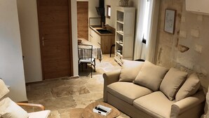 A living room with a beige sofa, two armchairs, a coffee table, and a kitchen area in the background. - Opposite Les Arenes and La Major (Arles)